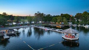 A marina with docked boats, a floating structure with seating, and a backdrop of trees and buildings. - Swan #11 Graceland Cottages (Lavigne)