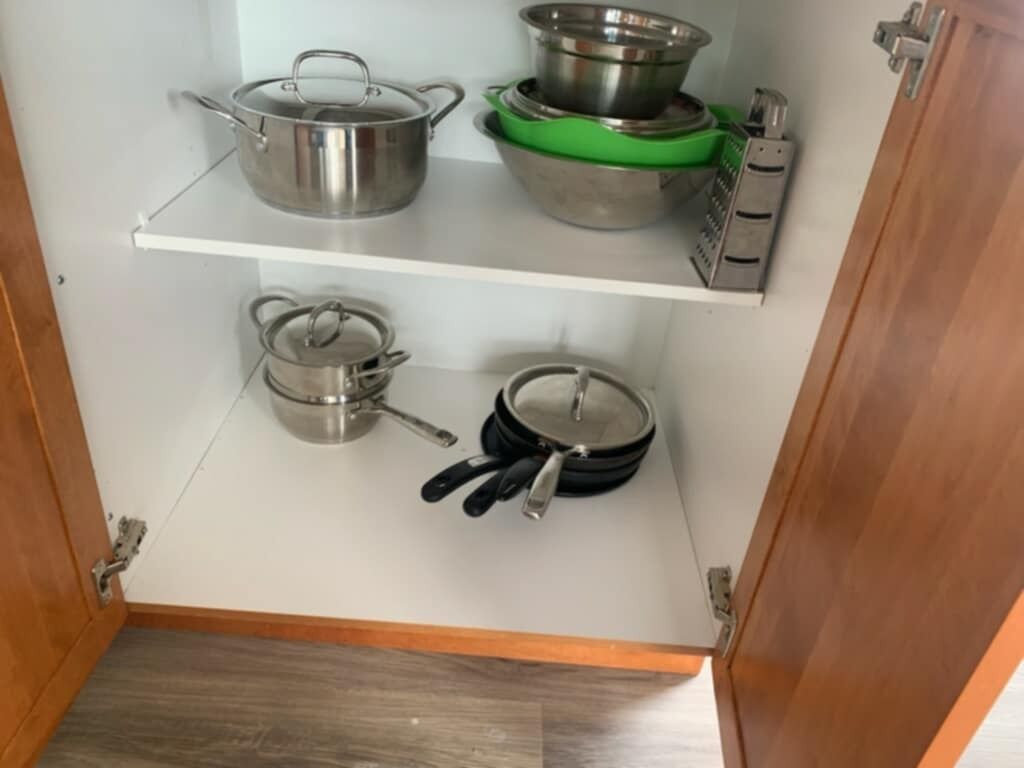 Una cocina con utensilios de acero inoxidable en estantes, una estufa eléctrica verde y un colgador para ollas.
