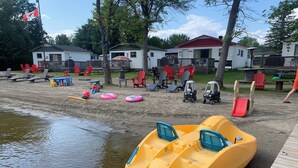 A lakeside area with a dock, inflatable boats, and beach chairs. - Swan #11 Graceland Cottages (Lavigne)