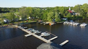 A marina with boats docked at wooden piers, surrounded by lush greenery and residential buildings. - Swan #11 Graceland Cottages (Lavigne)
