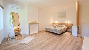 A bedroom with a bed, a bedside table, a mirror, a small fireplace, and a wooden wardrobe. - La Grande Clémente, 2 flats (Toulon)