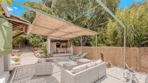 A covered outdoor patio with wicker furniture, a barbecue area, and a stone pathway leading to a staircase. - La Grande Clémente, 2 flats (Toulon)