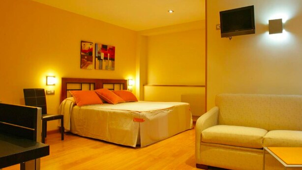 Une chambre d’hôtel avec un lit, un canapé, un bureau et une télévision.