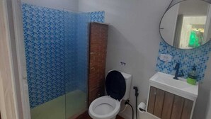 A bathroom with a tiled shower, a toilet, a sink, and a mirror. - Cozy chalet surrounded by nature in a gated community (101) (Parque Rizzo Cotia)