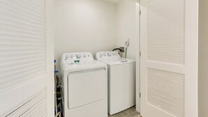 Une buanderie équipée de deux machines à laver à chargement frontal blanches et d’un sèche-linge.
