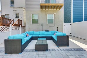 A sectional sofa with blue cushions and a matching ottoman in an outdoor patio area.