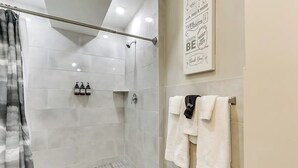 Un espace douche moderne avec une porte en verre, un porte-serviettes muni de plusieurs serviettes et une affiche motivante accrochée au mur.