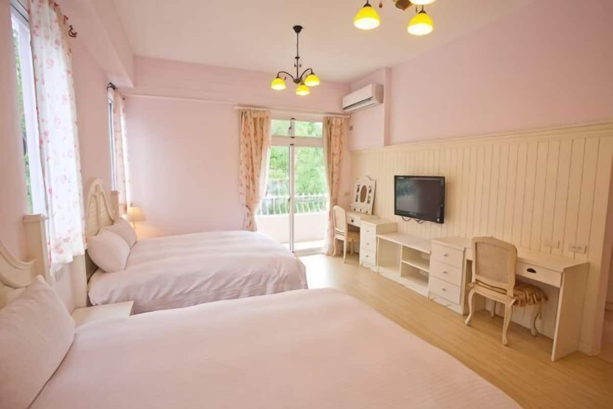 Une chambre avec deux lits, un bureau, une chaise, une télévision et un balcon.