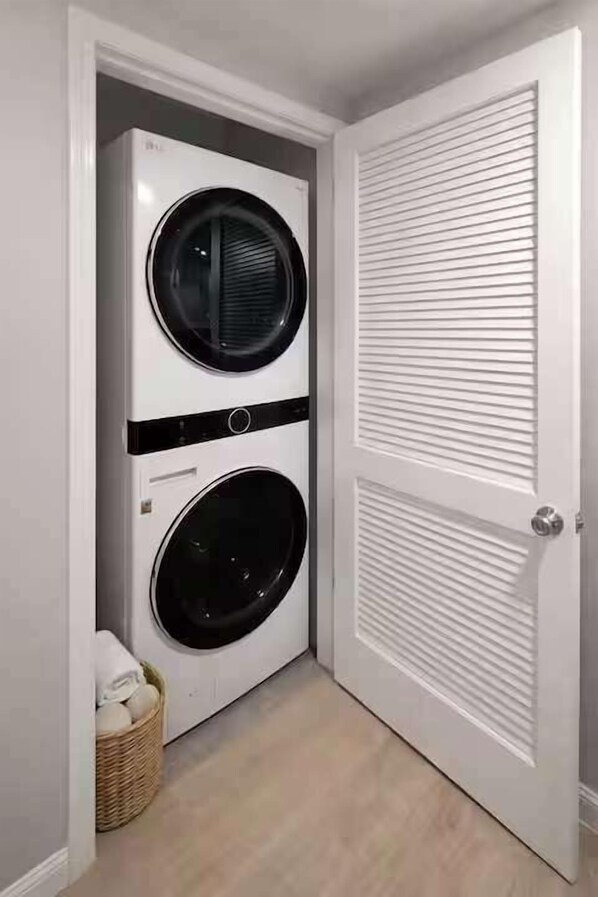A laundry room with two stacked front-loading washing machines and a closed door. - Cozy Rooftop Home, Near Downtown Newark, EWR & NYC (Newark)