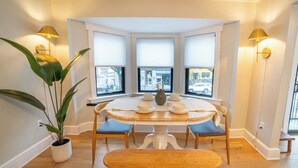 A dining area with a round table, four chairs, a bench, and two wall-mounted lamps. - Prime Location on Main Street (Stroudsburg)