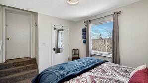Ein Schlafzimmer mit Bett, einem Fenster mit Blick, einer Tür und einer Treppe.