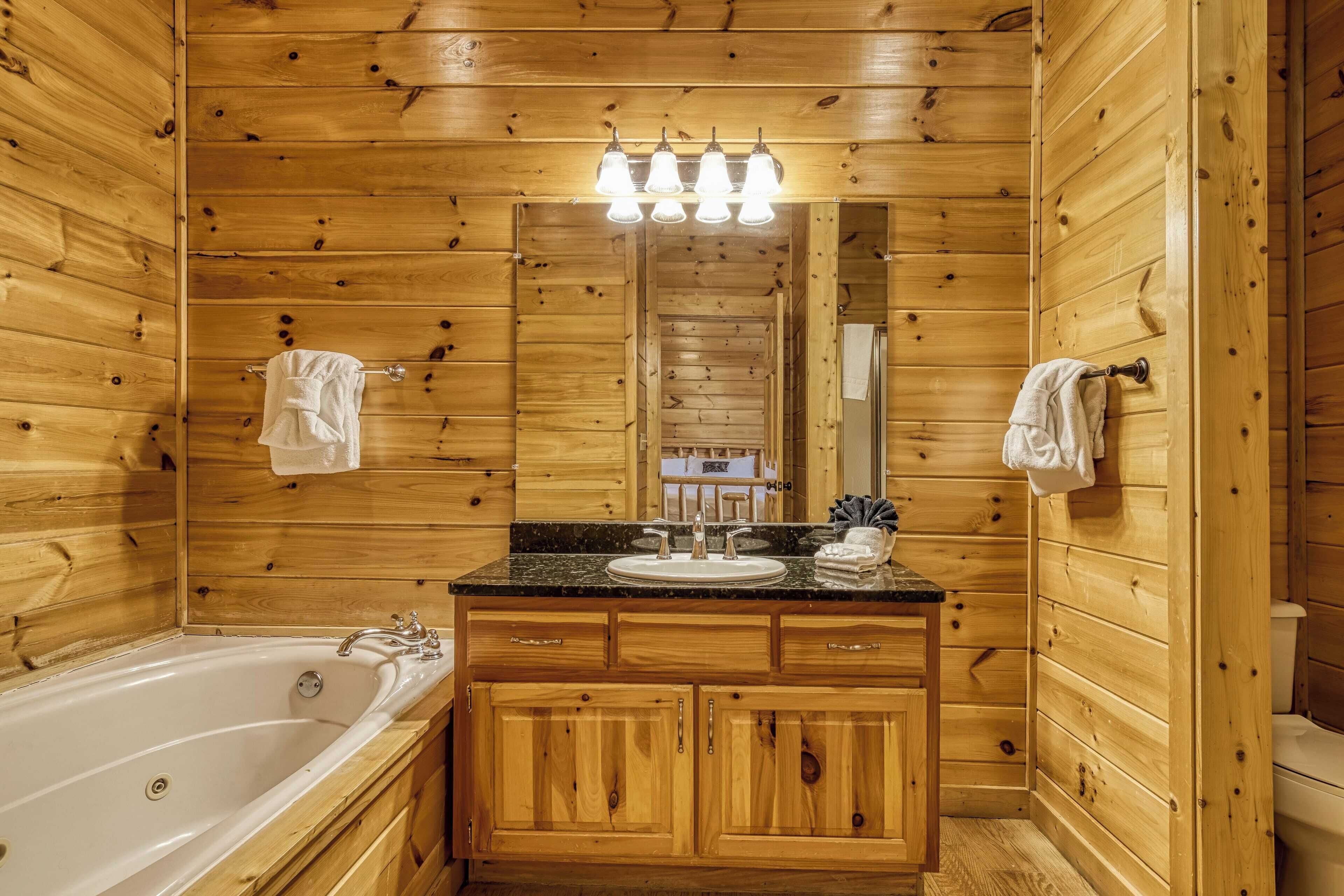 A wooden cabin bathroom with a bathtub, sink, and wooden cabinets.