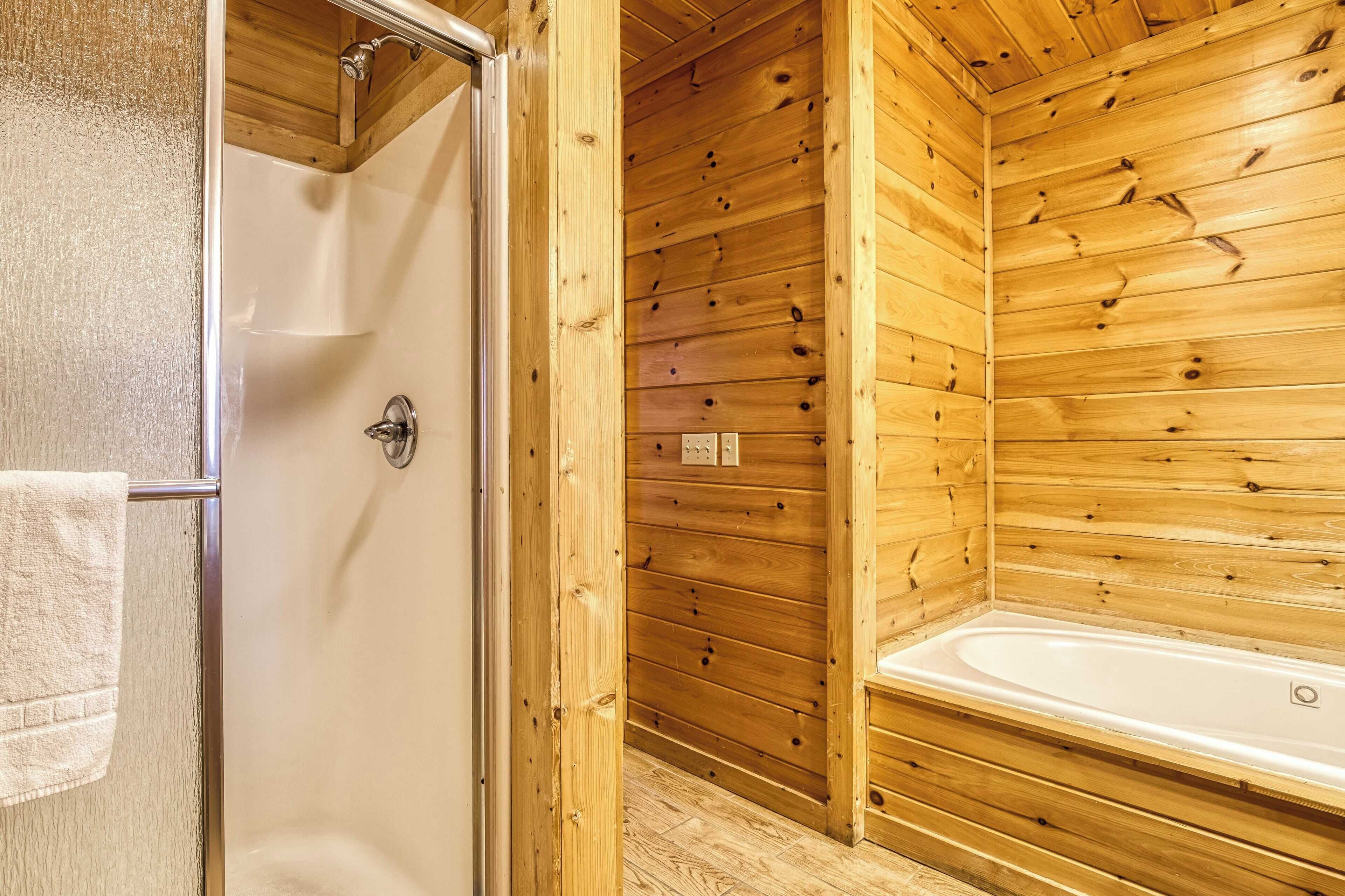 A wooden cabin bathroom with a shower, a bathtub, and a wooden wall.