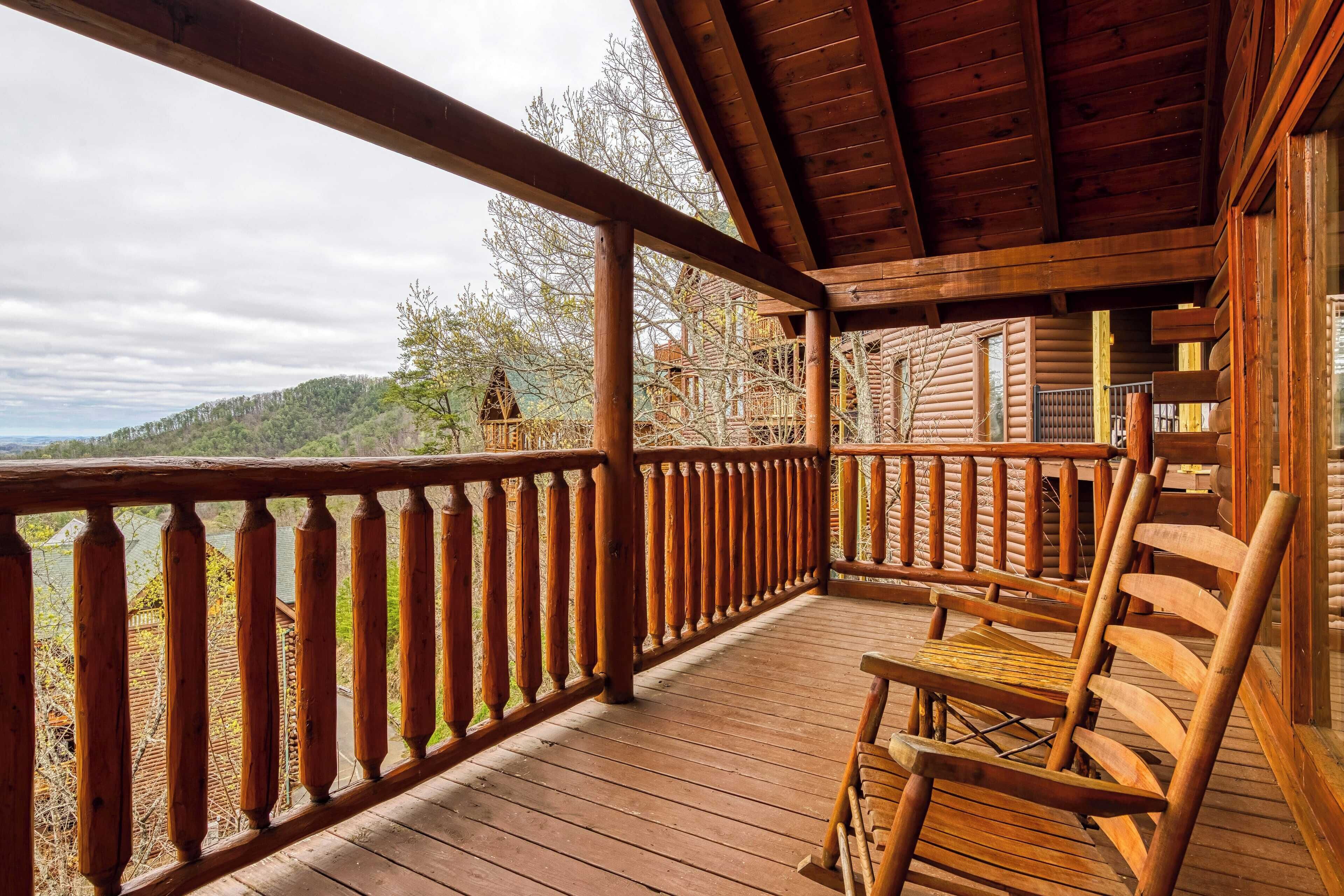A wooden deck with a railing, a wooden chair, and a view of a forested hillside.