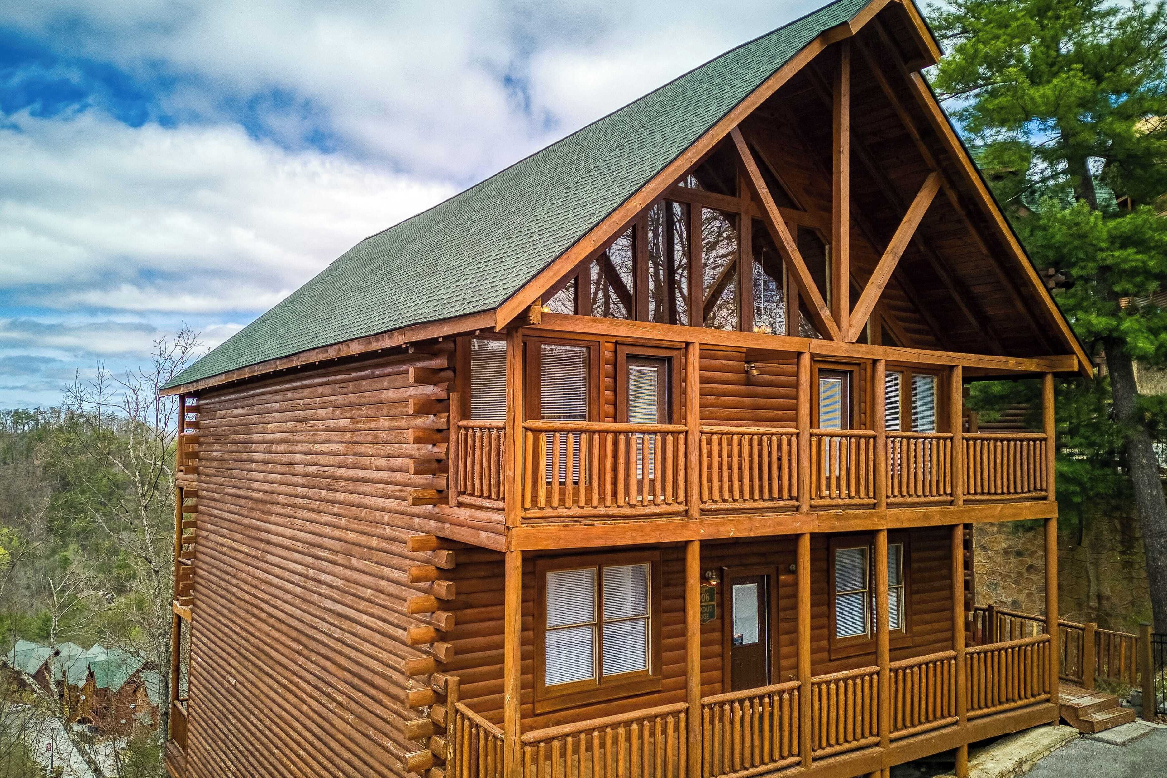 A log cabin with a balcony, multiple windows, and a steeply pitched roof.