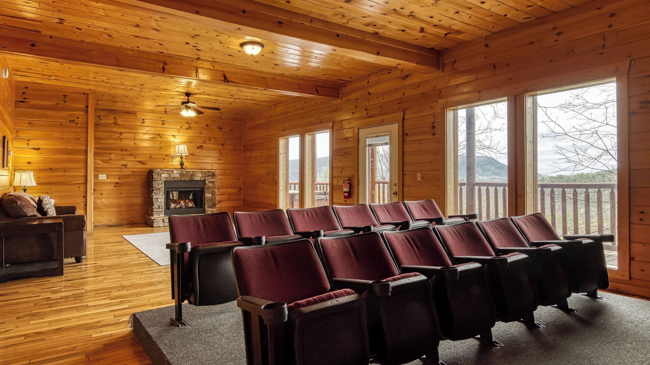 A log cabin interior with a fireplace, seating area, and large windows.