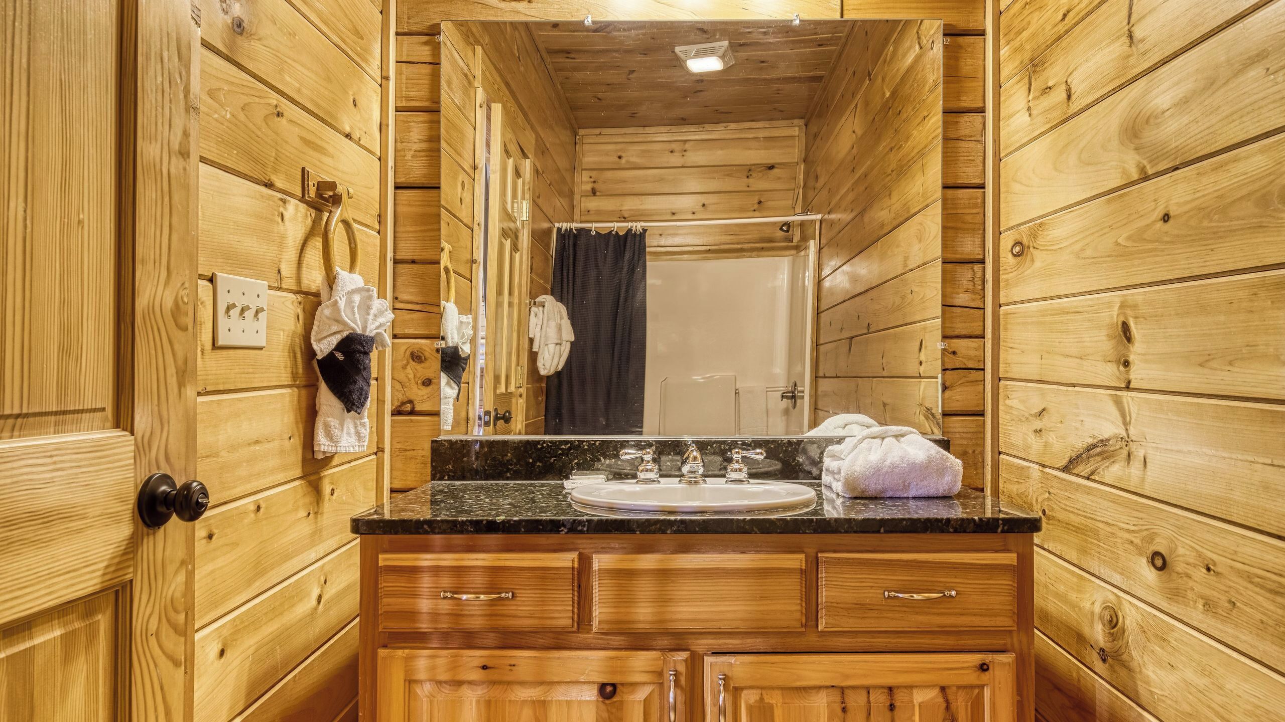 A wooden cabin bathroom with a sink, mirror, and towel rack.