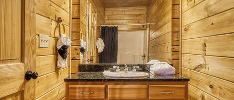 A wooden cabin bathroom with a sink, mirror, and towel rack.
