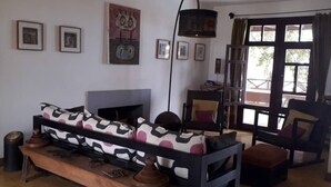 A living room with a sofa, a fireplace, a wooden bench, and a dining table. - Niokobokk  (Ndiebene Gandiol)