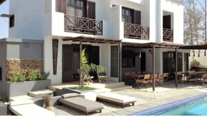A modern two-story house with a covered patio, outdoor seating, and a swimming pool. - Niokobokk  (Ndiebene Gandiol)