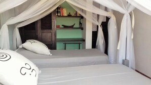 A room with two beds under a canopy, a green wall, and a shelf with books and decorative items. - Niokobokk  (Ndiebene Gandiol)