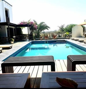 Ein rechteckiger Swimmingpool mit Holzterrasse und Liegestühlen.