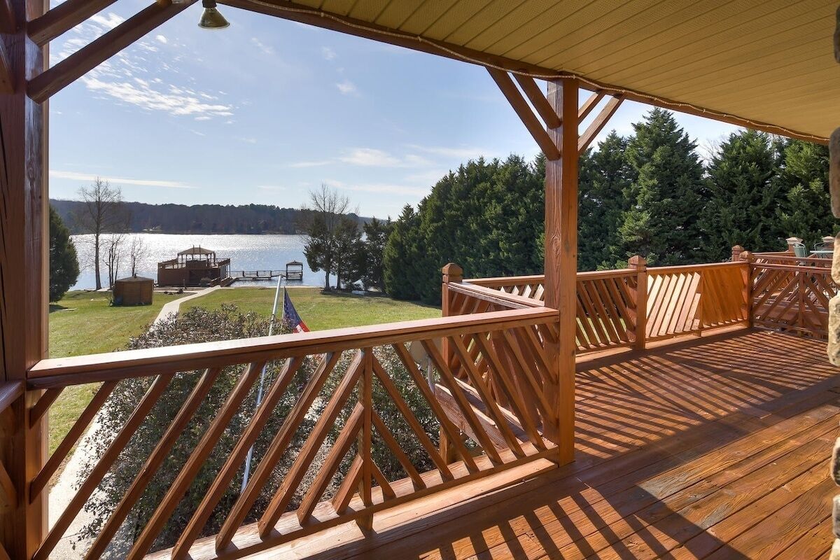 A wooden deck with a view of a lake and forest.