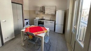 Eine kleine Küche mit Esstisch, Stühlen, einer Waschmaschine und einem Kühlschrank.