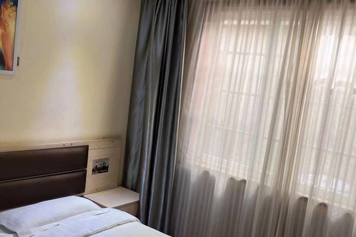 Un dormitorio con cama, mesita de noche, un cuadro en la pared y cortinas de gasa.