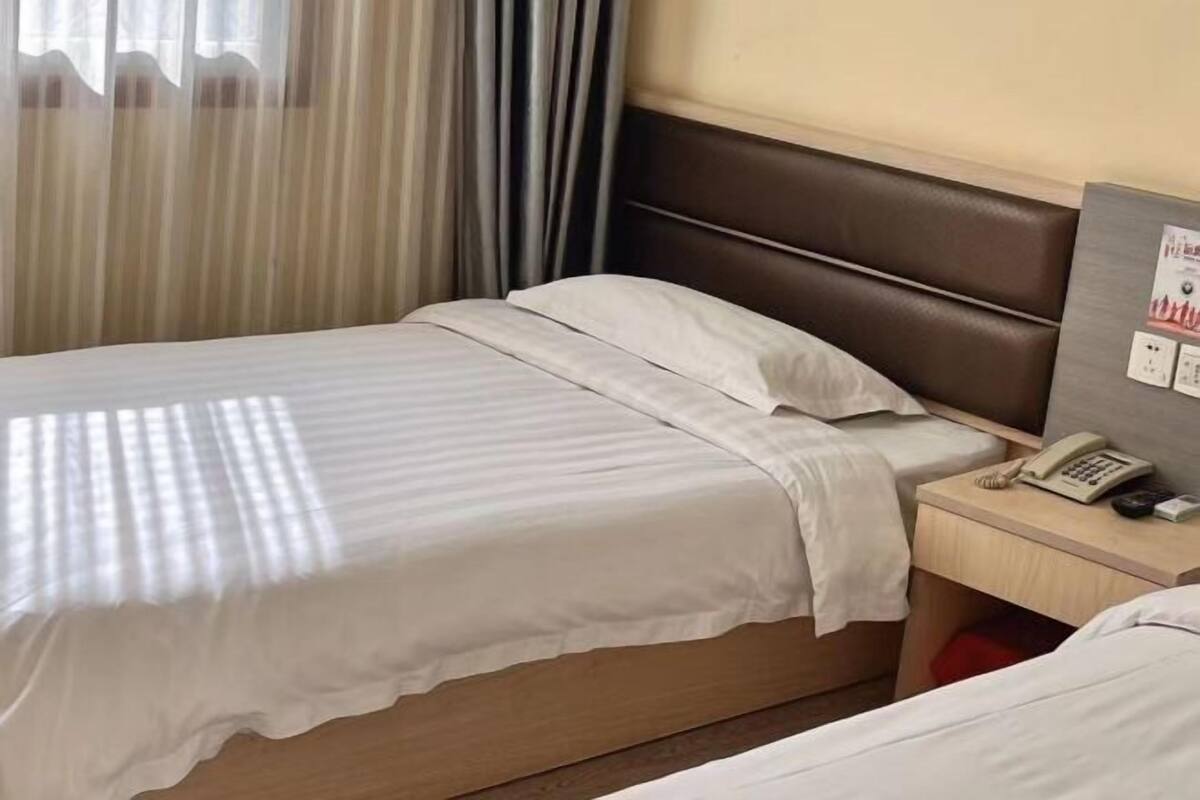 Habitación de hotel con cama, mesita de noche con teléfono y un interruptor de luz en la pared.