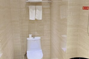 A bathroom with a toilet, a towel rack with two towels, and a red sign on the wall.