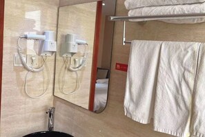 A bathroom with a mirror, two hair dryers, a towel rack with towels, and a sink.