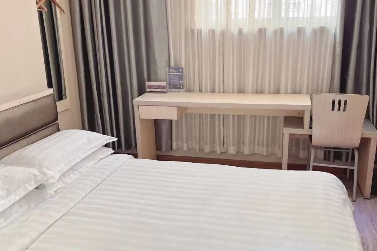 Una habitación de hotel con una cama, un escritorio y una silla.