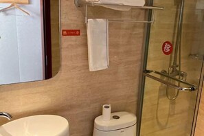 A bathroom with a glass shower enclosure, a white sink, and a toilet.