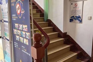 A staircase with a wooden handrail and a poster on the wall. - NANYUAN INN Hotel (Hangzhou Huan Cheng North Road Baoshanqiao Subway Station) (Hangzhou)