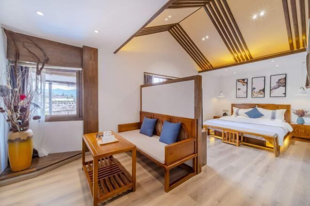 A bedroom with a bed, a sofa, a small table, and a window with a view.