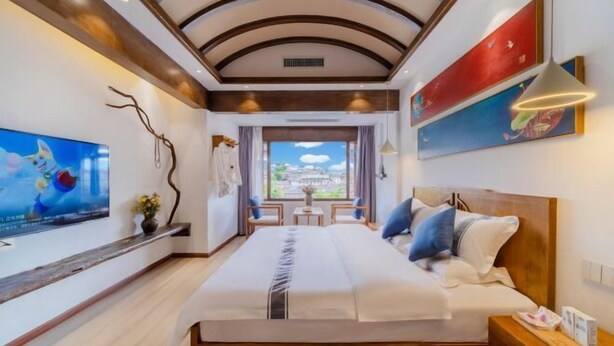 A modern hotel room with a large bed, a TV, and a view of the city. - Jixiang Guanjing Inn (Lijiang Old Town Dashuiche Branch) (Lijiang)