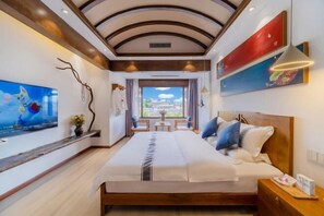 A modern hotel room with a large bed, a TV, and a view of the city.