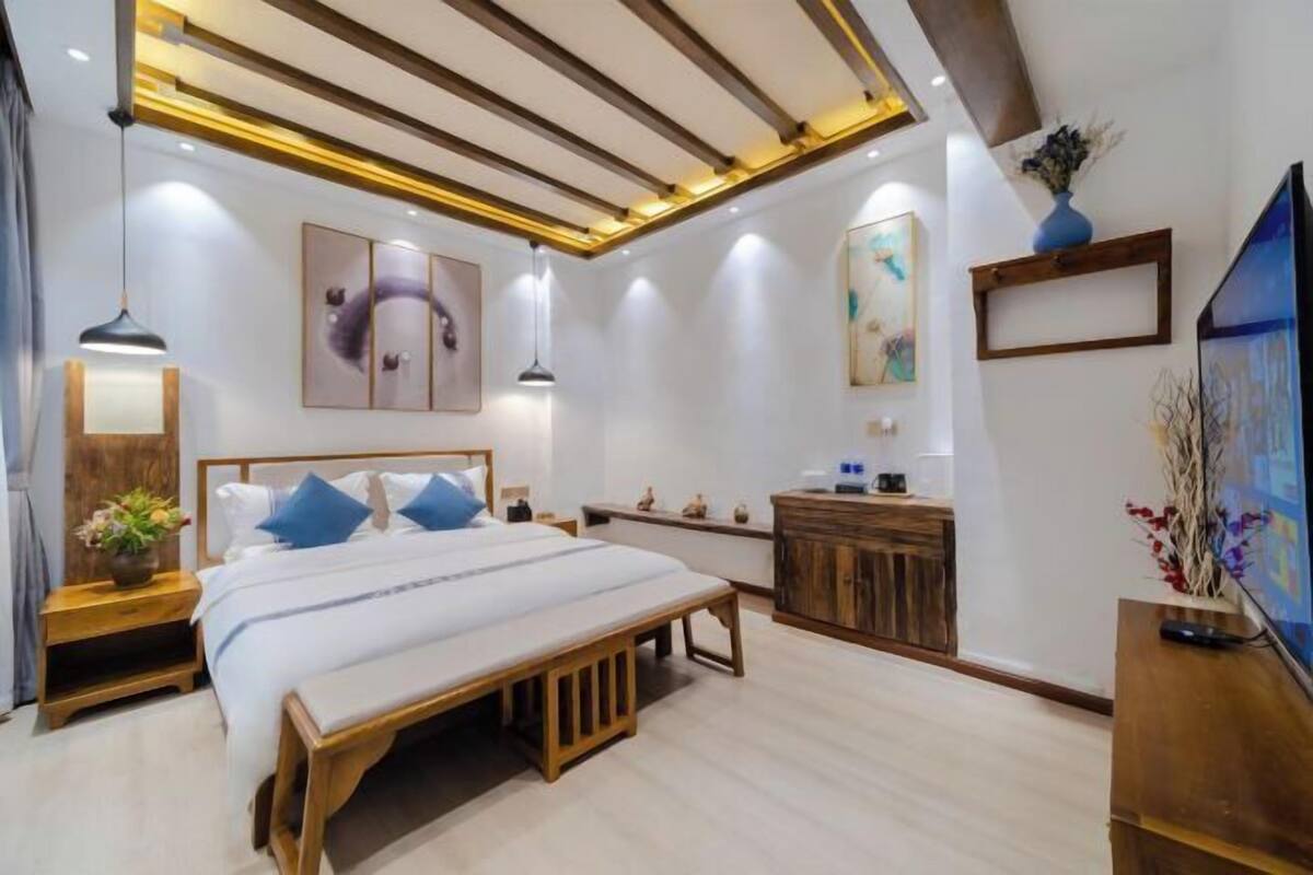 A modern bedroom with a bed, bedside tables, a dresser, artwork, and a TV.
