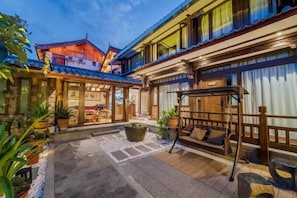 Une cour intérieure de style japonais traditionnel, avec des tatamis, un banc en bois et une balançoire suspendue.