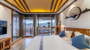 A hotel room with a large bed, a TV, a balcony with a view, and a clock on the wall. - Jixiang Guanjing Inn (Lijiang Old Town Dashuiche Branch) (Lijiang)