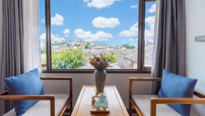 A room with two wooden chairs, a small table, and a window with a view of a cityscape. - Jixiang Guanjing Inn (Lijiang Old Town Dashuiche Branch) (Lijiang)
