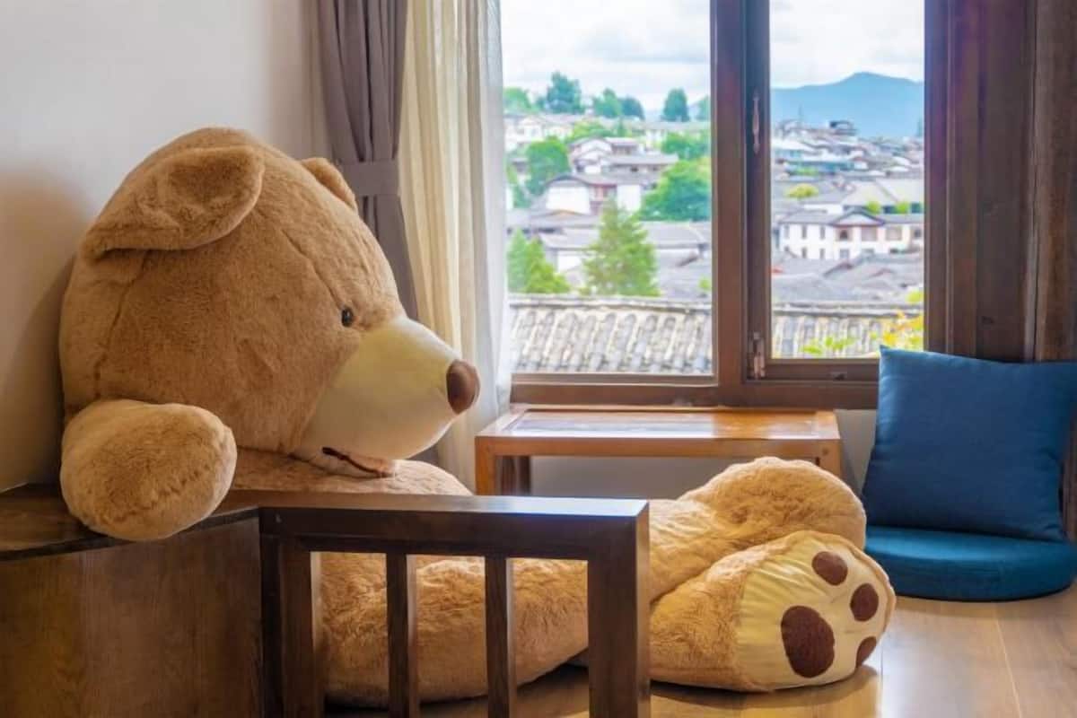 A large teddy bear on a chair, a small table, and a blue cushion.