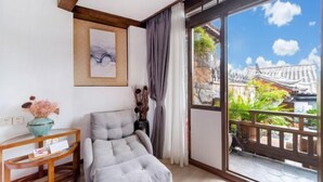 A modern room with a grey sofa, a wooden console table with a vase, and a large window with a view of traditional architecture. - Jixiang Guanjing Inn (Lijiang Old Town Dashuiche Branch) (Lijiang)