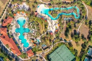 Vue aérienne d’un complexe hôtelier doté d’une grande piscine centrale, d’un toboggan aquatique sinueux et de plusieurs petites piscines.