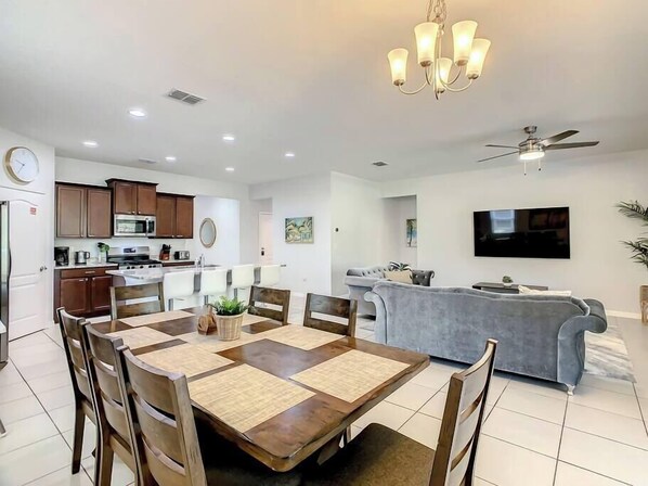 A modern kitchen with dark wooden cabinets, a microwave, and a dining area with a wooden table and chairs.