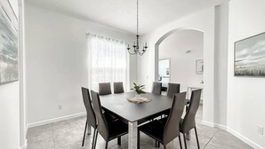 Ein stilvolles Esszimmer mit einem rechteckigen Tisch, sechs Stühlen und einer Pendelleuchte.