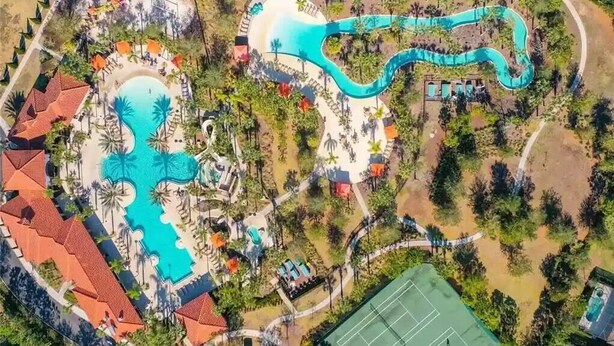 Eine Luftaufnahme eines Resorts mit einem großen zentralen Pool, kleineren Pools und einer wellenförmigen Wasserrutsche.