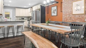 Eine moderne Küche mit weißen Schränken, einer großen Kochinsel und einem Essbereich mit Holztisch und Barhocker.
