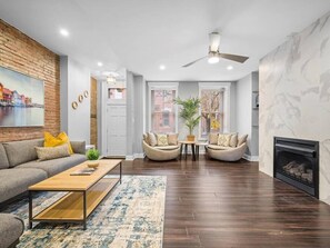 A modern living room with a sofa, two armchairs, a coffee table, and a fireplace. - Stylish 4Bdr Loft Home, North Shore, City Skyline with Free Street Parking (Pittsburgh)